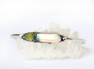 peridot and angel aura quartz bracelet with silver band sitting on crystal quartz 